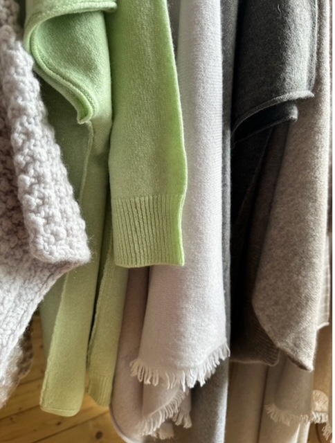 Cashmere_Modelle in Beige-, Braun- und Gruentoenen haengen nebeneinander